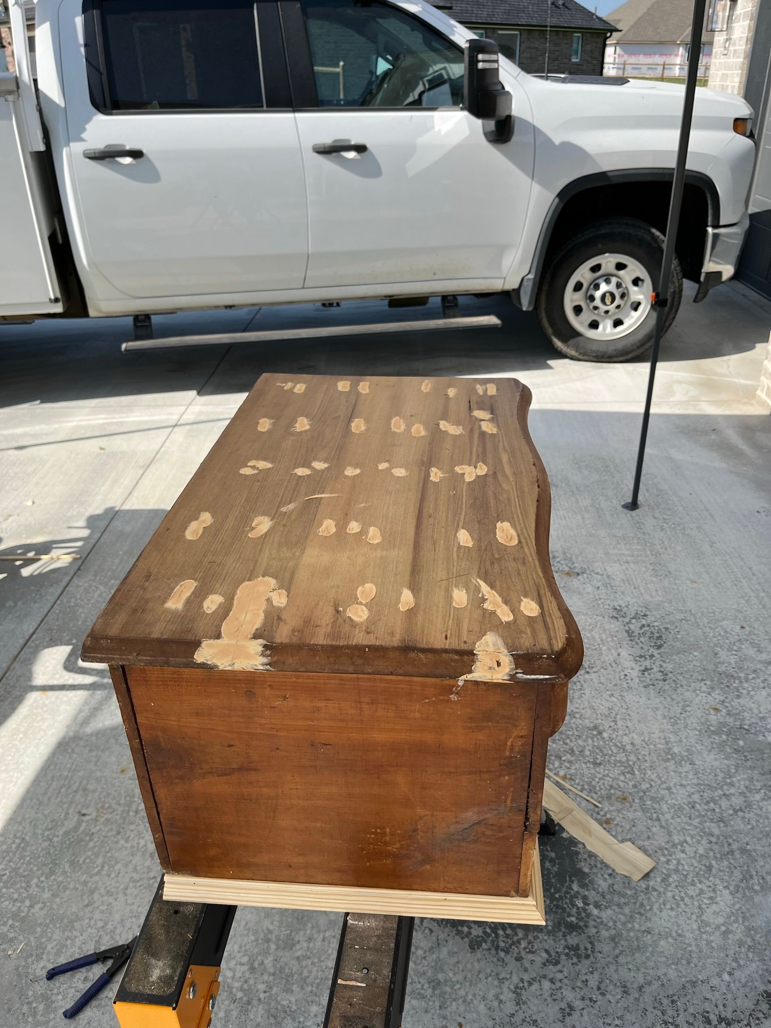 Wooden chest with peeling top; white truck in the background. Outdoor setting.