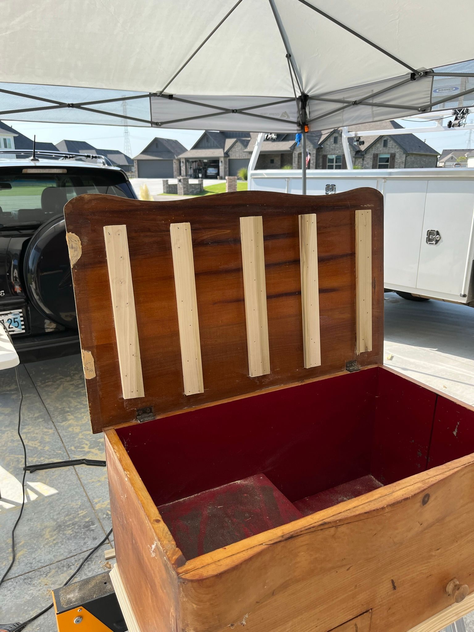 Open wooden chest with a dark brown lid, cream-colored reinforcement strips, and a red interior under a white canopy.
