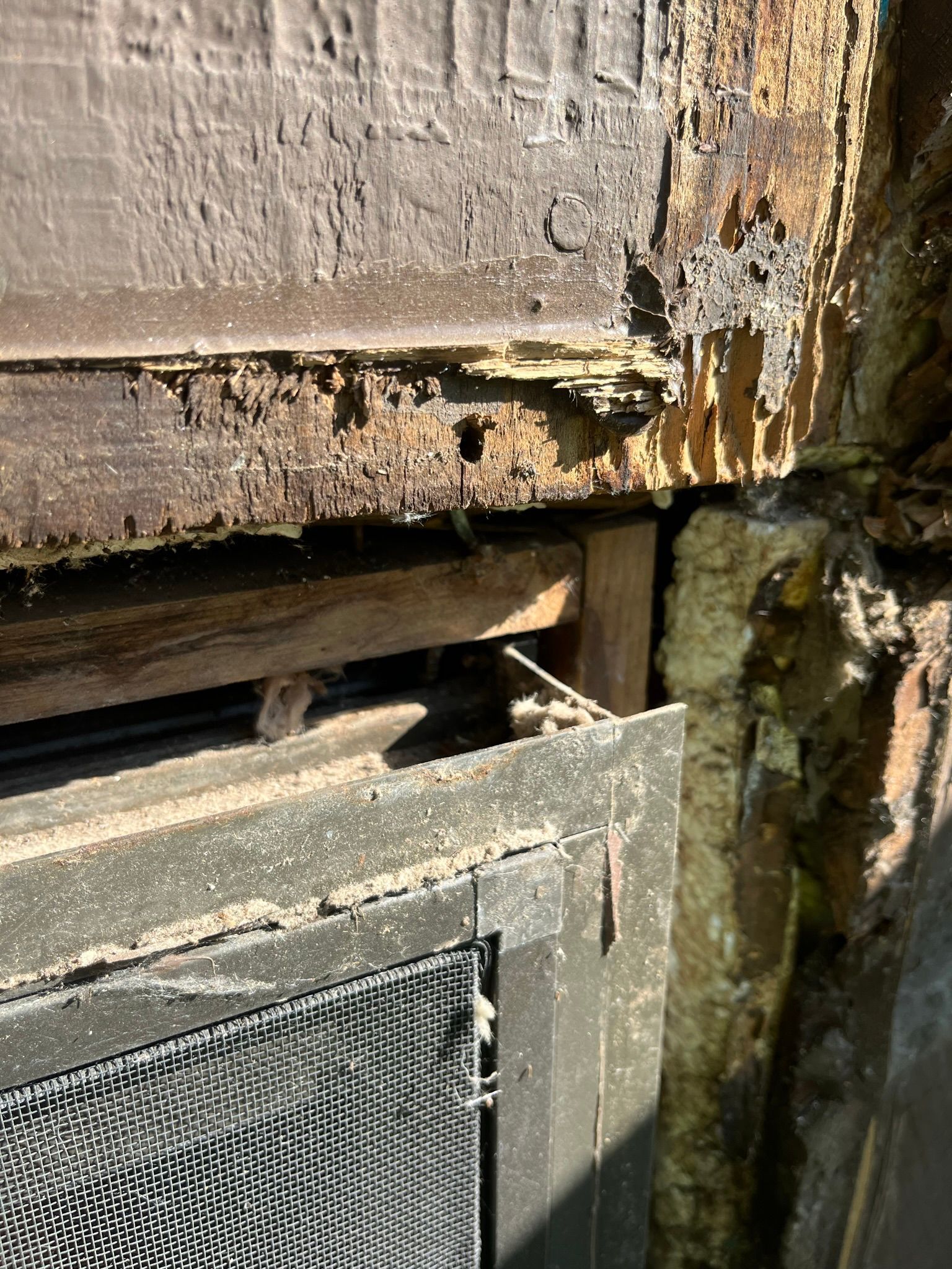 Damaged wooden window frame with signs of rot and decay near brick.