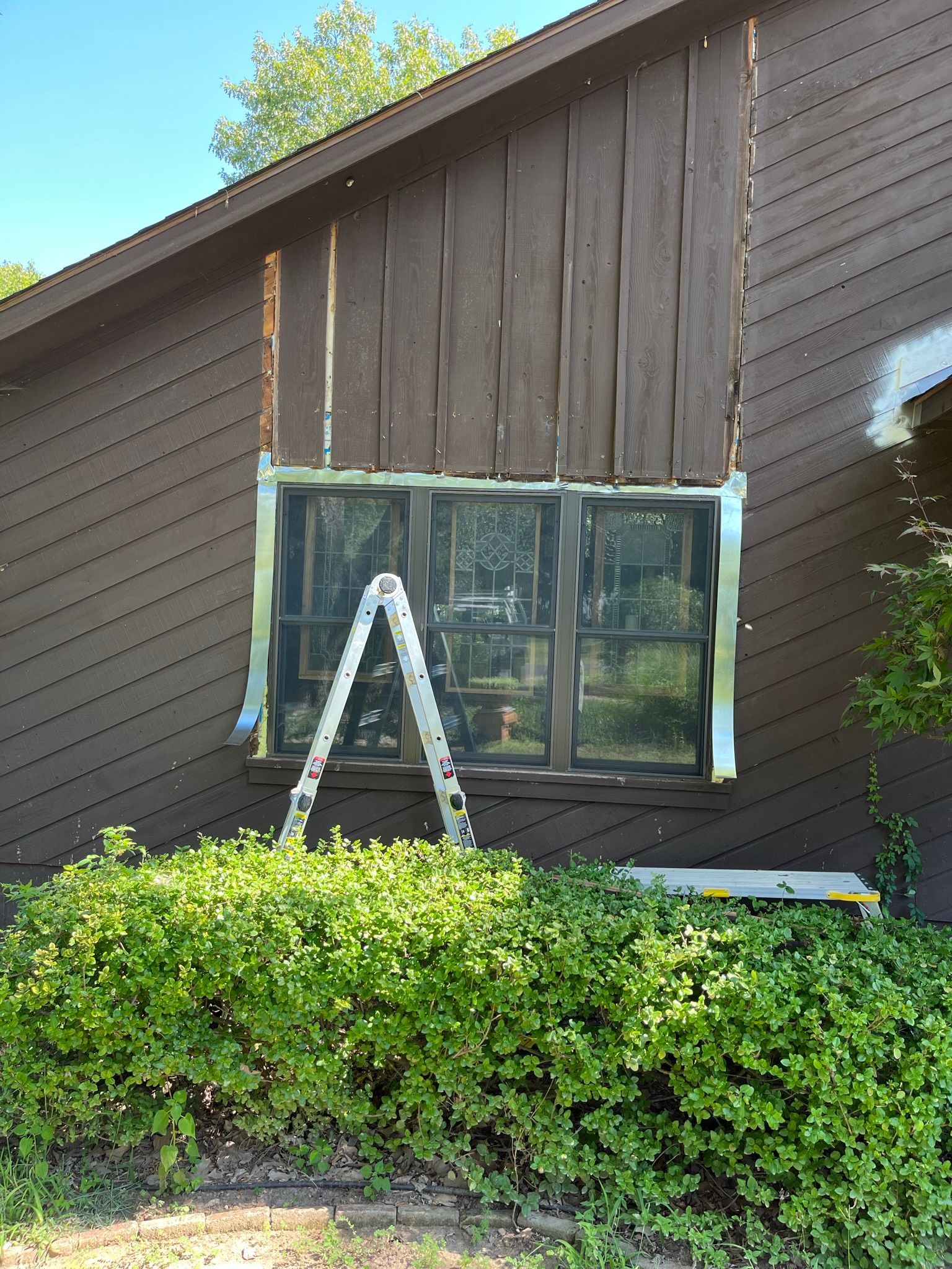 House exterior with a partially removed wall; a ladder stands next to a window.