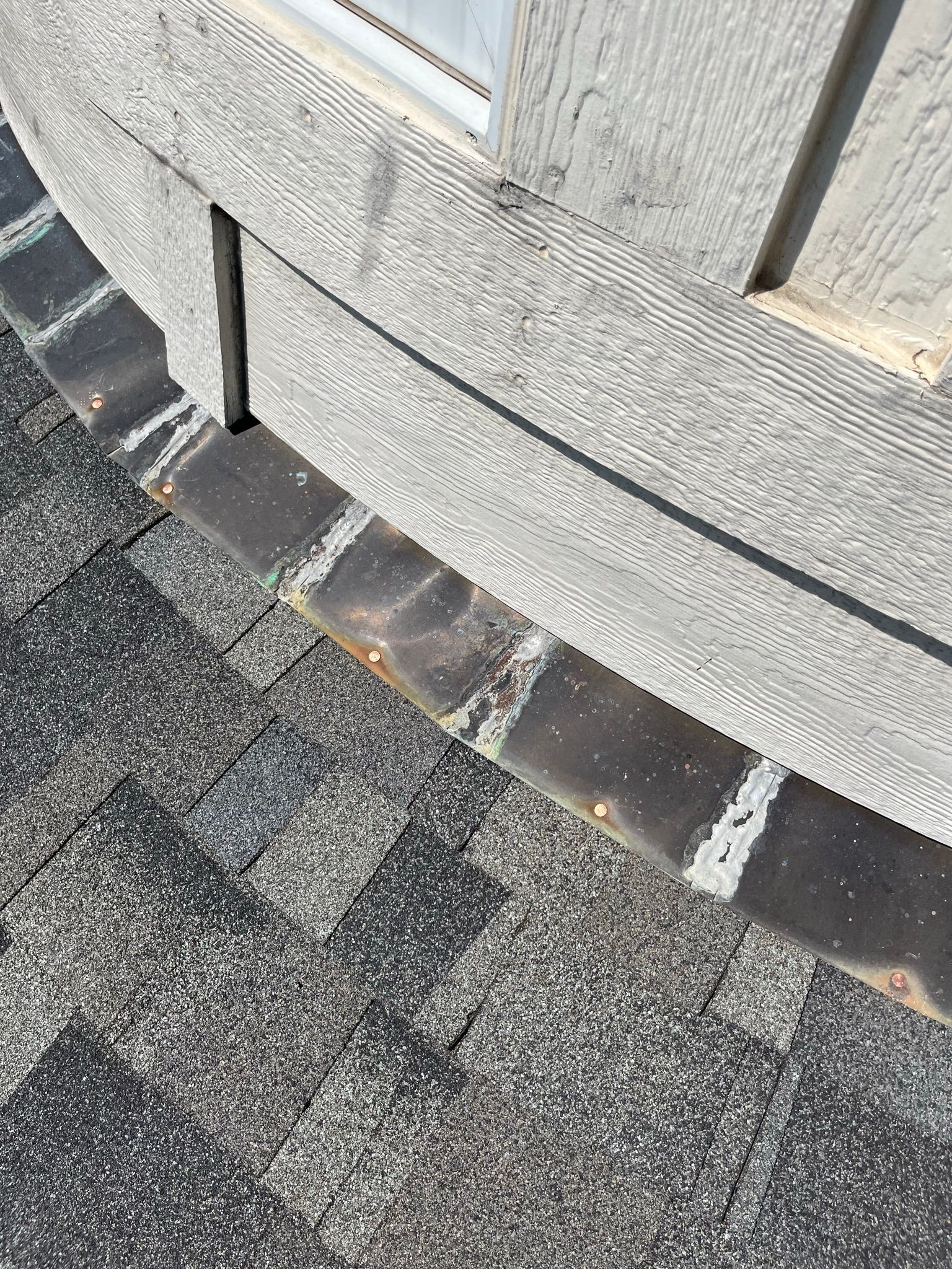 Close-up of a house exterior with weathered siding and roof shingles.