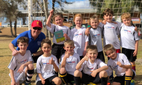 A group of young boys are posing for a picture with their coach.