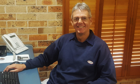 A man in a blue shirt is sitting in front of a computer