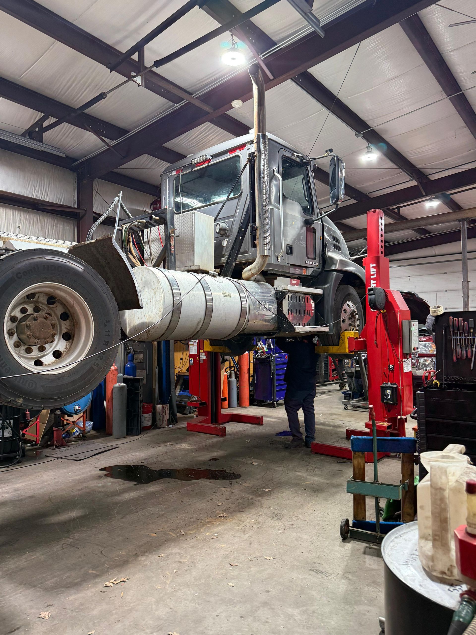 Semi-truck raised on a lift inside a repair shop. 