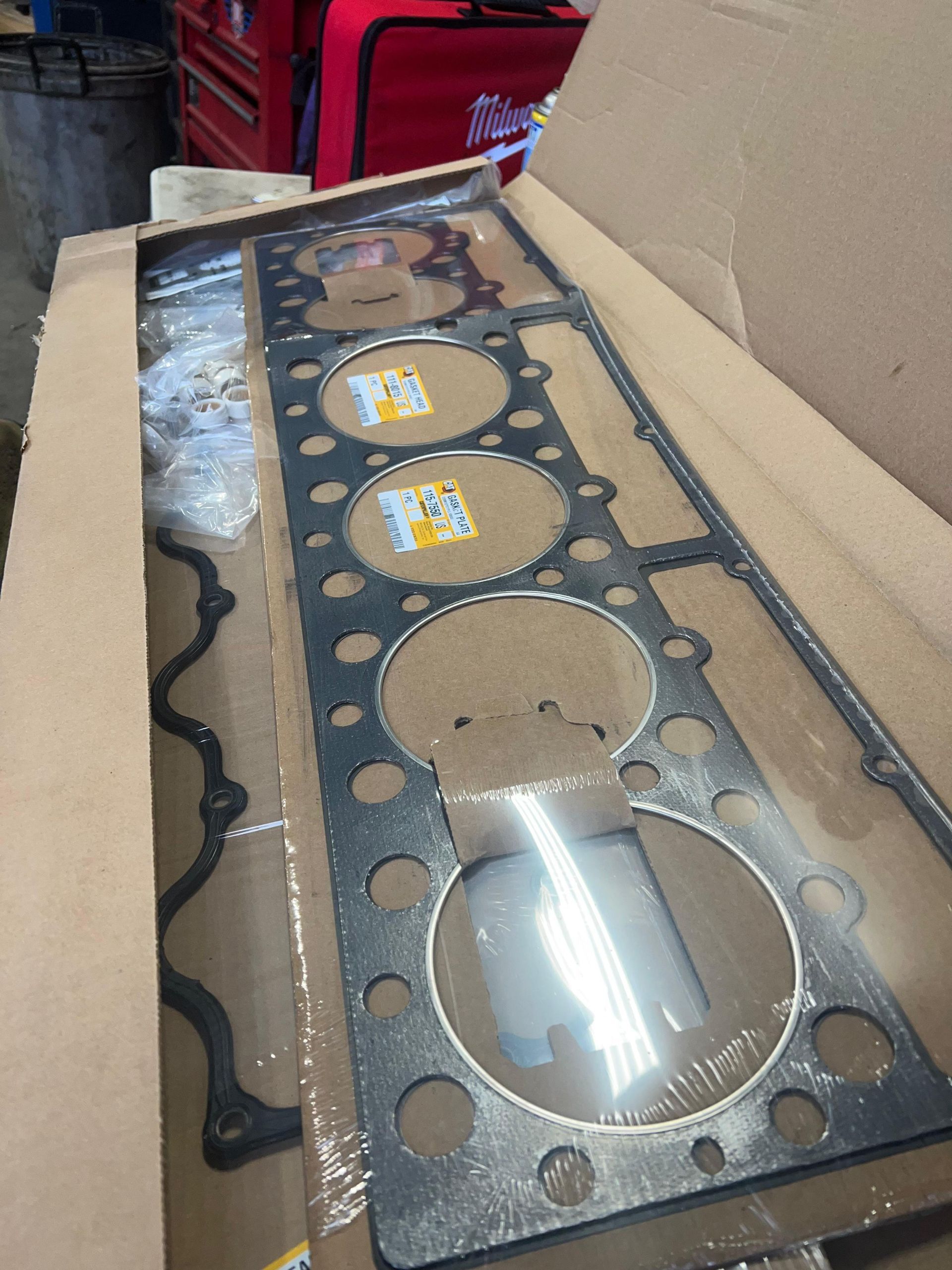 A new engine gasket set in a cardboard box, with gaskets visible.