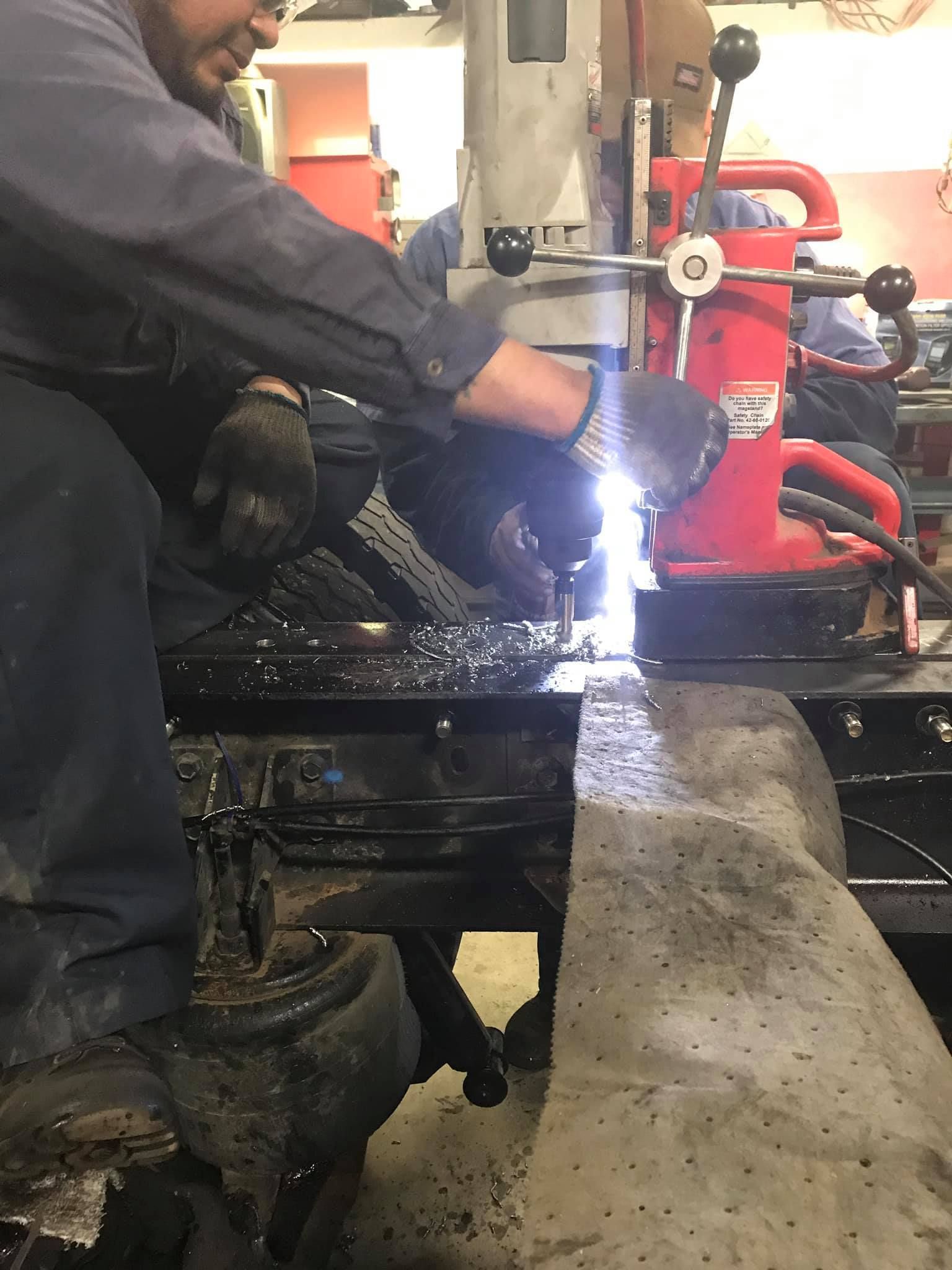 Person welding metal with a torch in a workshop setting. 