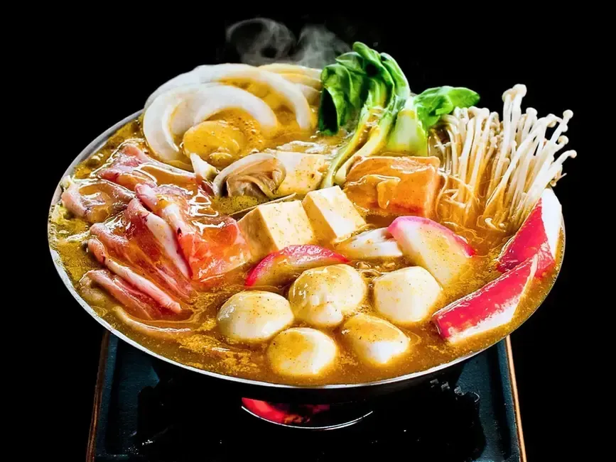 Korean hot pot with assorted vegetables, tofu, mushrooms, and seafood simmering in a round pot