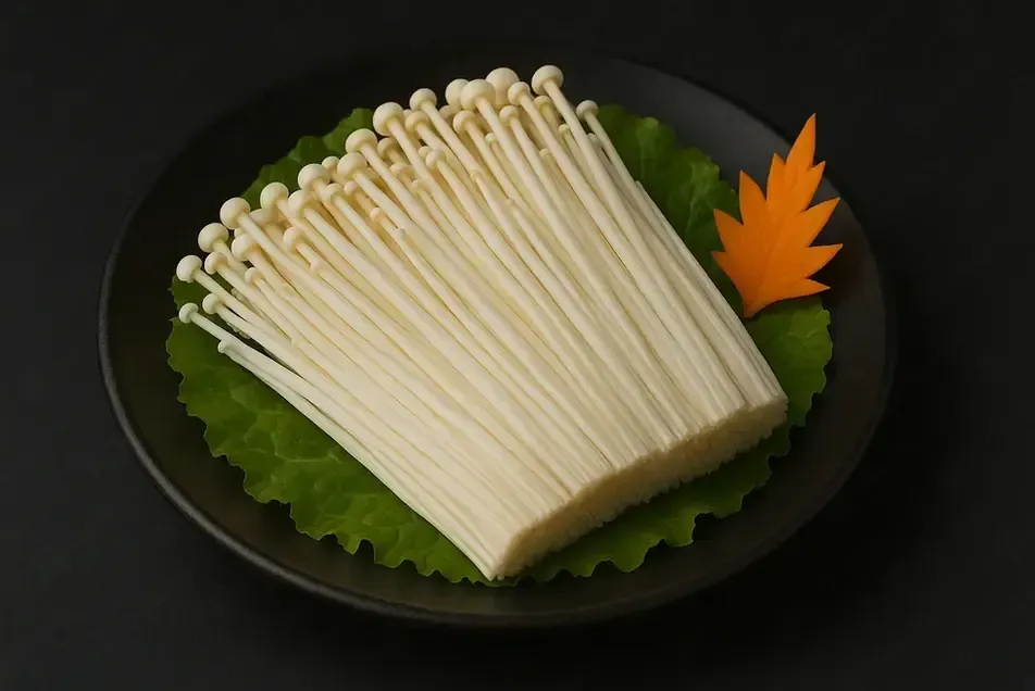 Enoki mushrooms on a black plate with green lettuce garnish and an orange leaf decoration