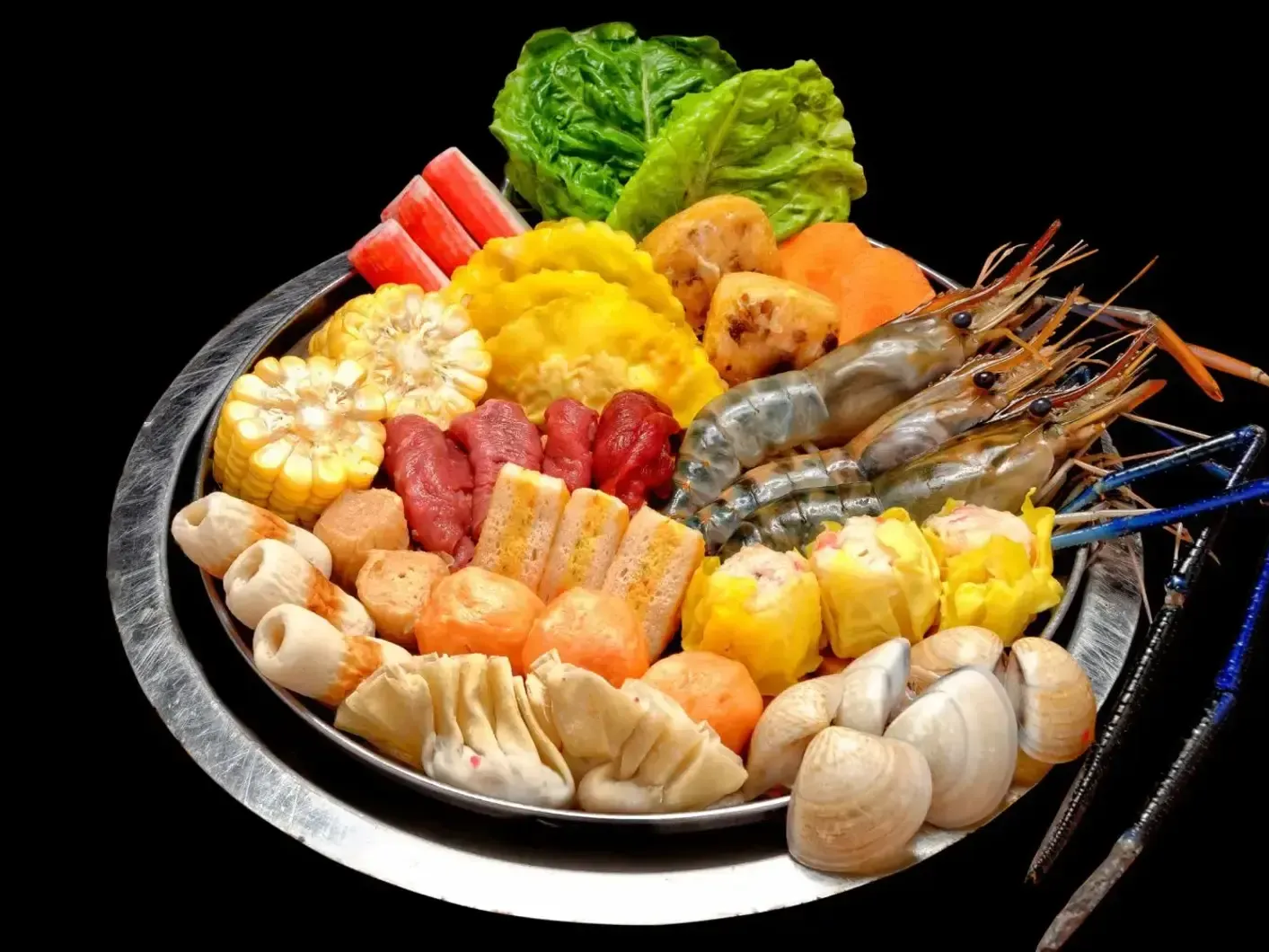Assorted seafood and vegetables arranged on a black platter, with shrimp, crab sticks, mushrooms, and lettuce.