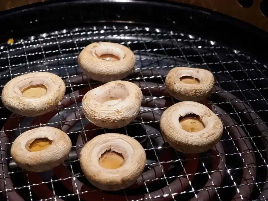 Seven plain donuts cooling on a wire rack in a black tray