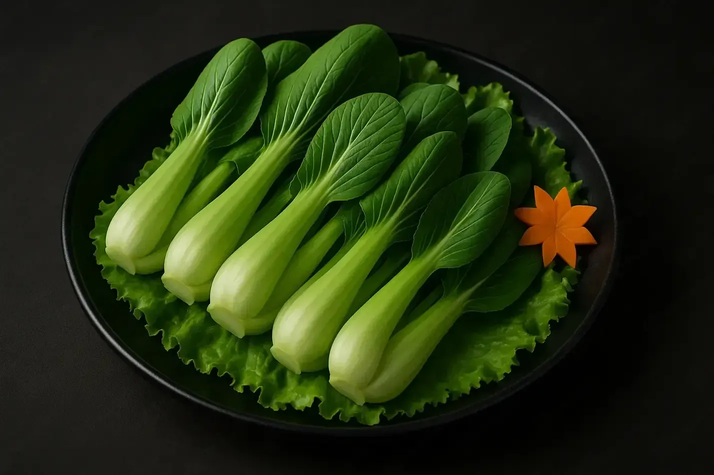Green bok choy arranged on a black plate with lettuce garnish and an orange carrot flower