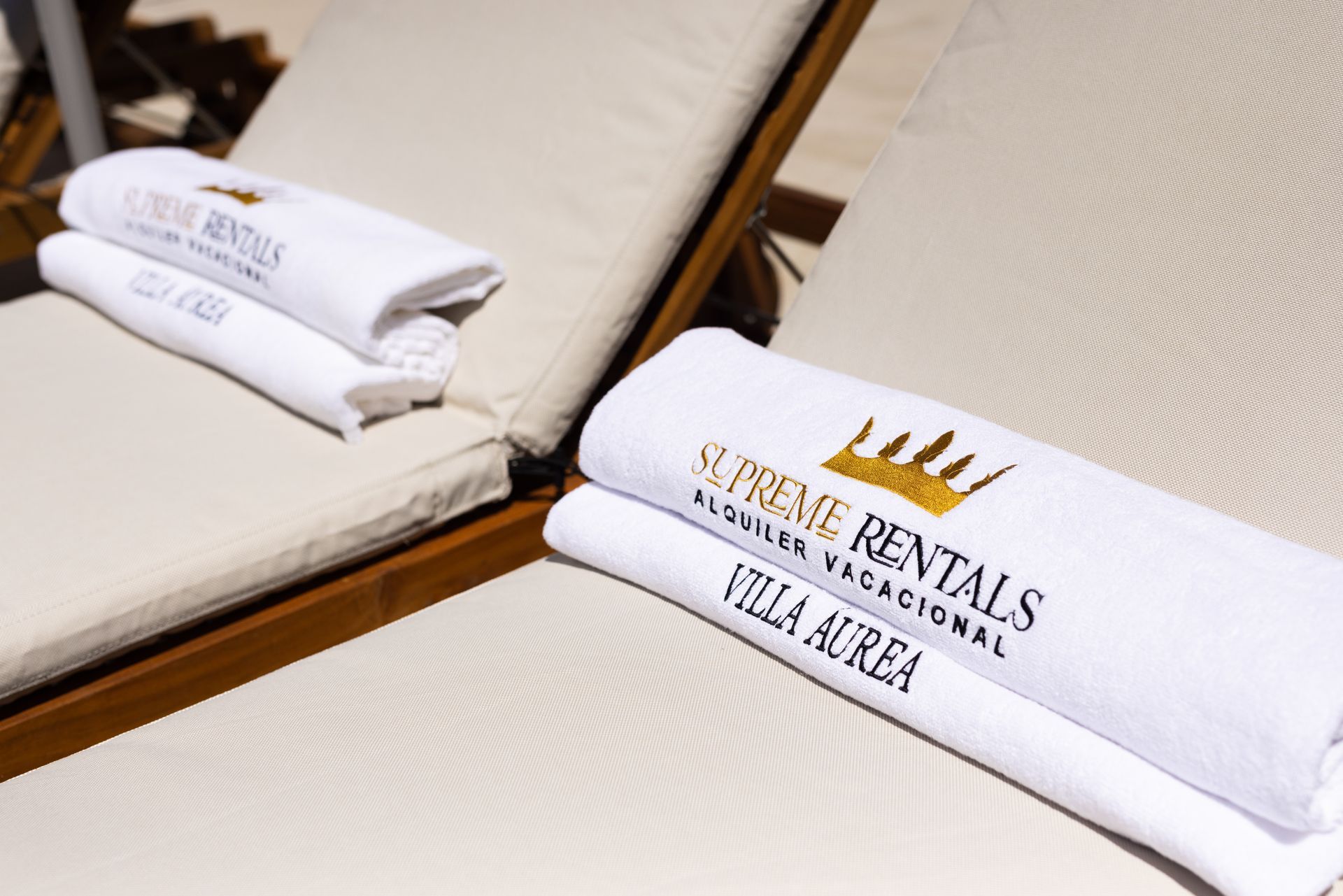 White resort lounge chairs with folded towels labeled “Riviera Rentals” and “Villa & Spa.”