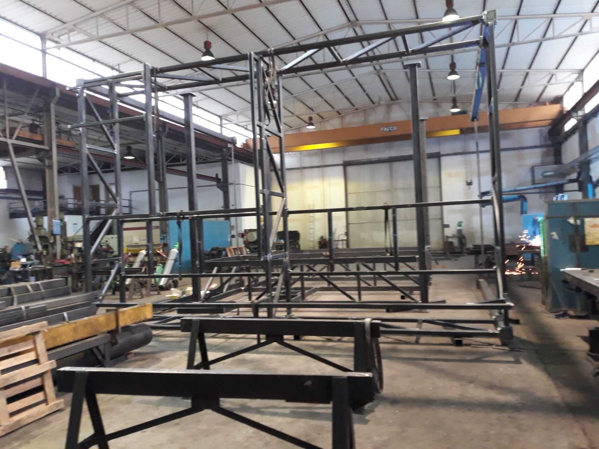 Un'officina metallurgica con una grande struttura in acciaio non verniciato in fase di costruzione al centro.