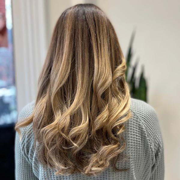 Back view of long wavy blonde hair with darker roots, worn loose indoors