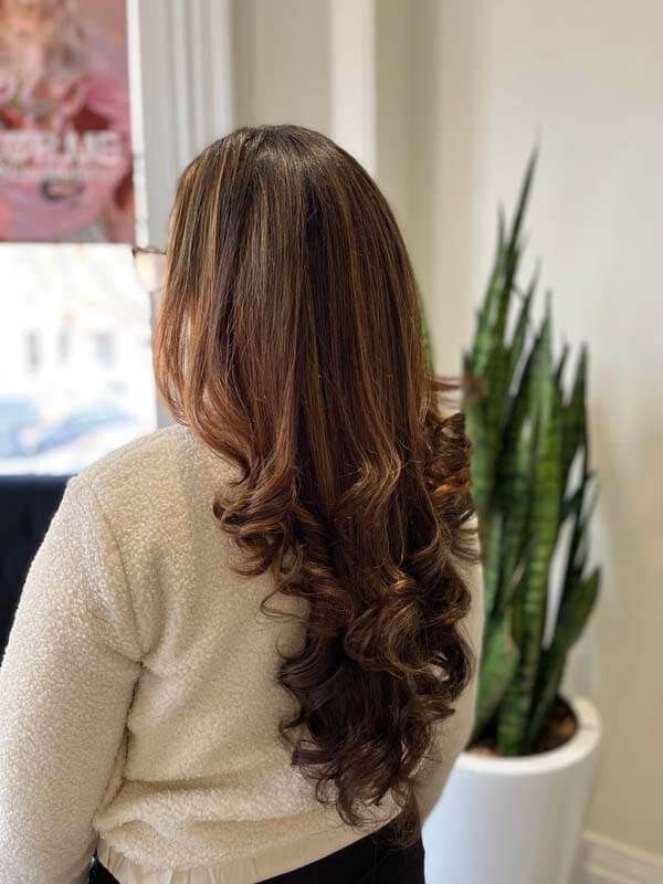 Woman with long wavy brown hair wearing a cream sweater