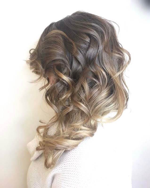 Side view of a loose, curled braid with dark-to-blonde ombré hair