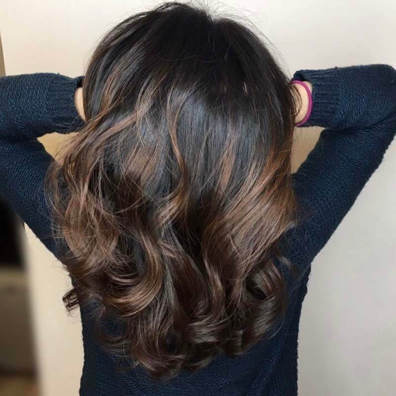 Back view of shoulder-length wavy dark brown hair with caramel highlights