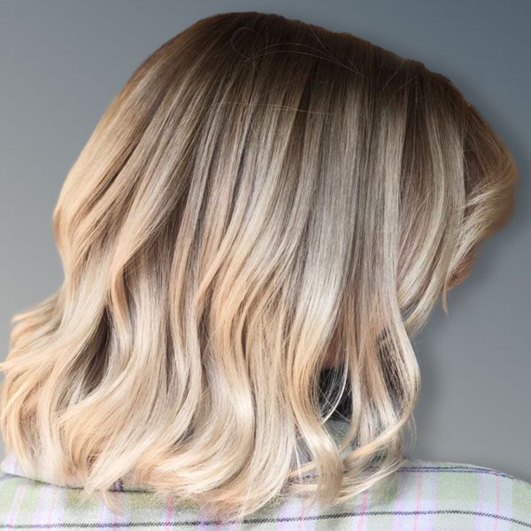 Blonde wavy bob haircut with dark roots, shown from the back