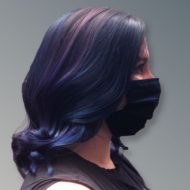 Side-profile of a person with dark wavy hair and a black face mask