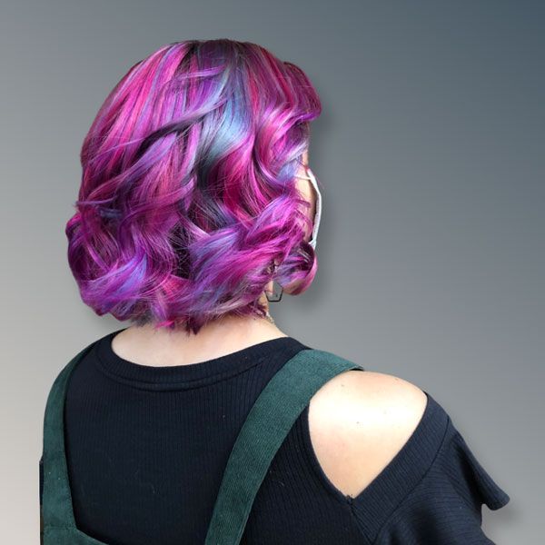 Person with short wavy hair dyed pink and purple