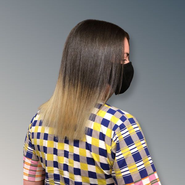 Person with straight ombré hair wearing a black face mask and blue-yellow plaid shirt