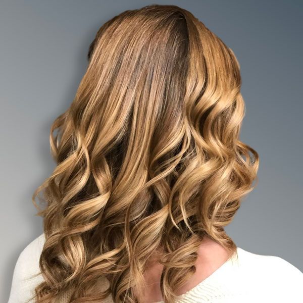 Wavy blonde-brown hair shown from the back against a gray background