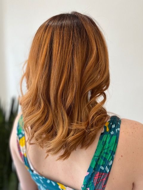 Back view of shoulder-length auburn wavy hair on a person in a colorful patterned top