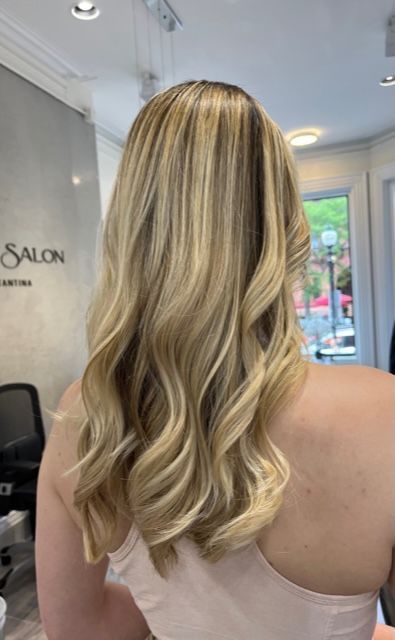 Blonde wavy hair styled in a salon, viewed from the back with soft curls.