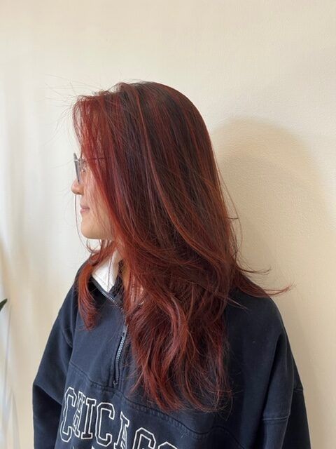 Side profile of a person with long red hair and glasses