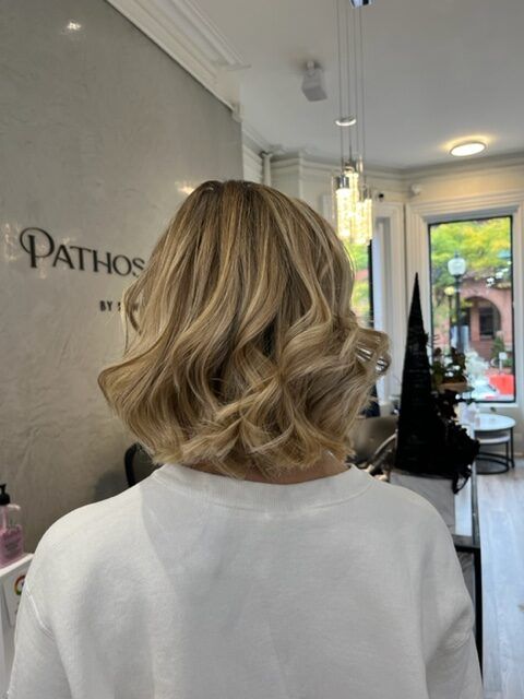 Short blonde wavy haircut shown from behind in a salon chair