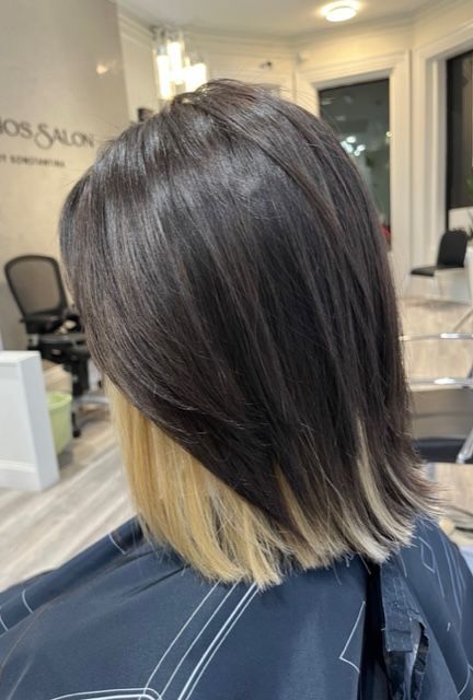Short layered dark hair with blonde ends in a salon chair
