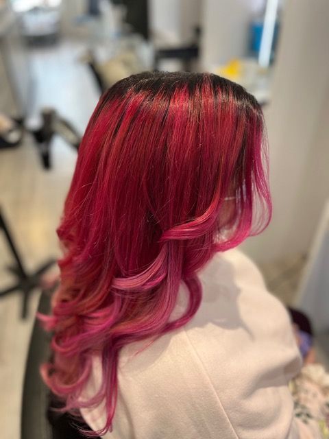 Salon hair with bright pink highlights and loose waves, viewed from the back.