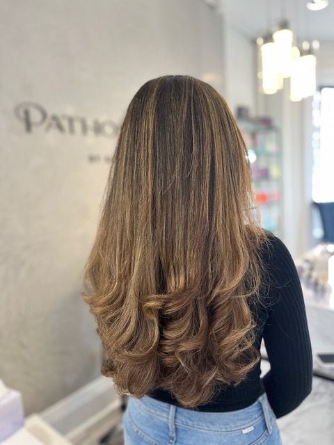 Back view of a woman with long brown hair in a salon