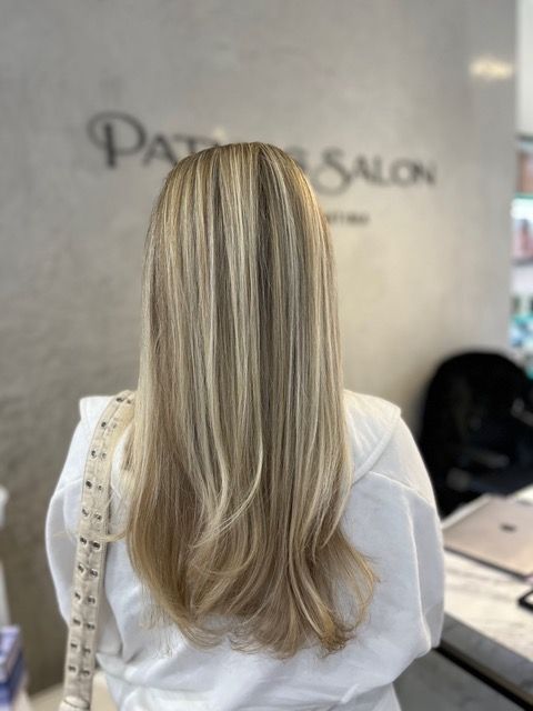 Long blonde hair with subtle highlights, viewed from behind in a salon chair