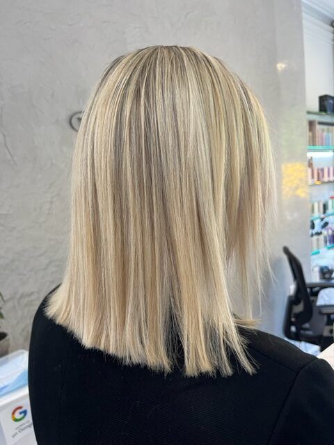 Blunt blonde bob haircut viewed from the back in a salon setting