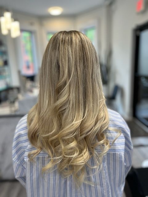 Blonde wavy hair styled in a salon, shown from behind