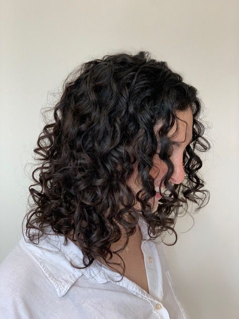 Side-profile portrait of a person with dark curly hair