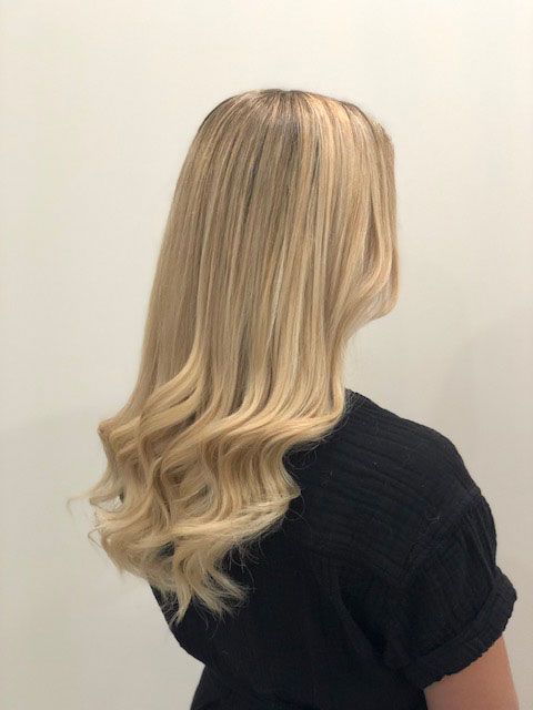 Blonde hair in loose waves on a person wearing a black top