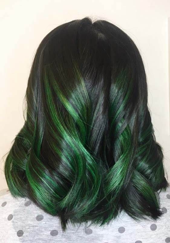 Dark shoulder-length wavy hair with black and emerald green highlights, seen from the back.
