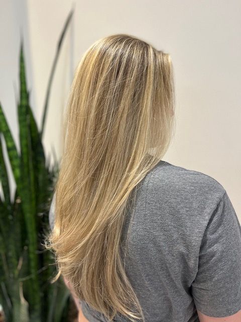 Long blonde hair cascading over a gray shirt