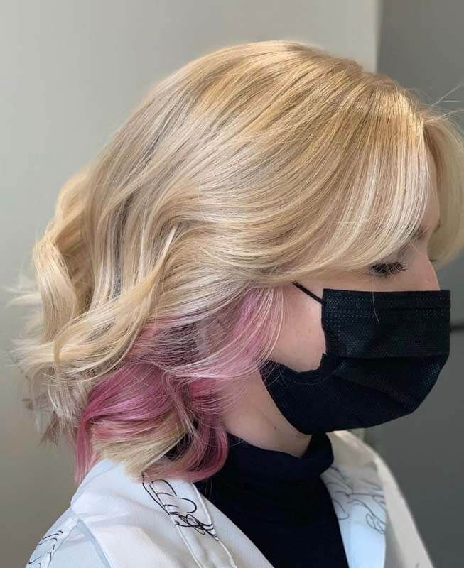 Blonde layered bob with pink ends, shown in profile wearing a black face mask.