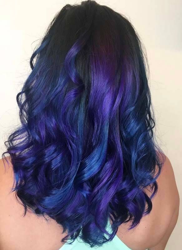 Back view of shoulder-length wavy hair with dark blue and purple highlights