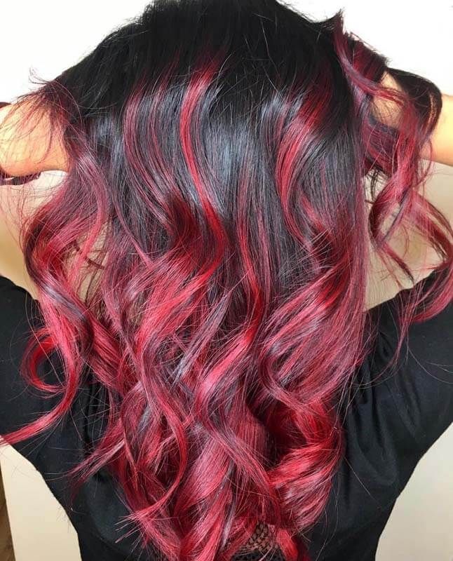 Long wavy black hair with vivid red highlights cascading down the back