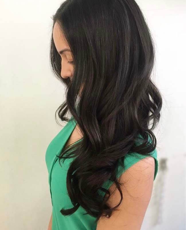 Side profile of a woman with long dark wavy hair
