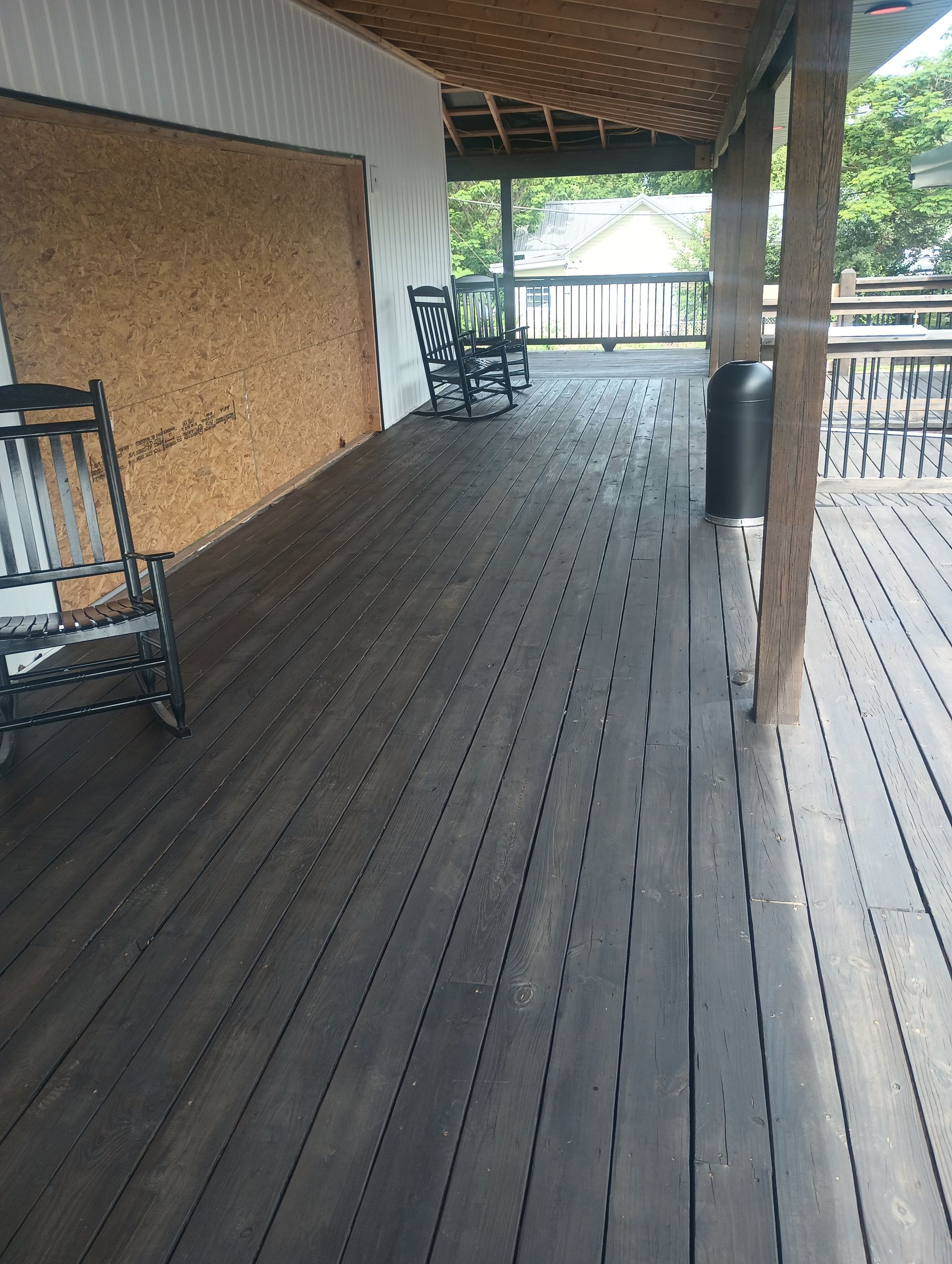 Covered wooden deck with benches and a railing overlooking greenery