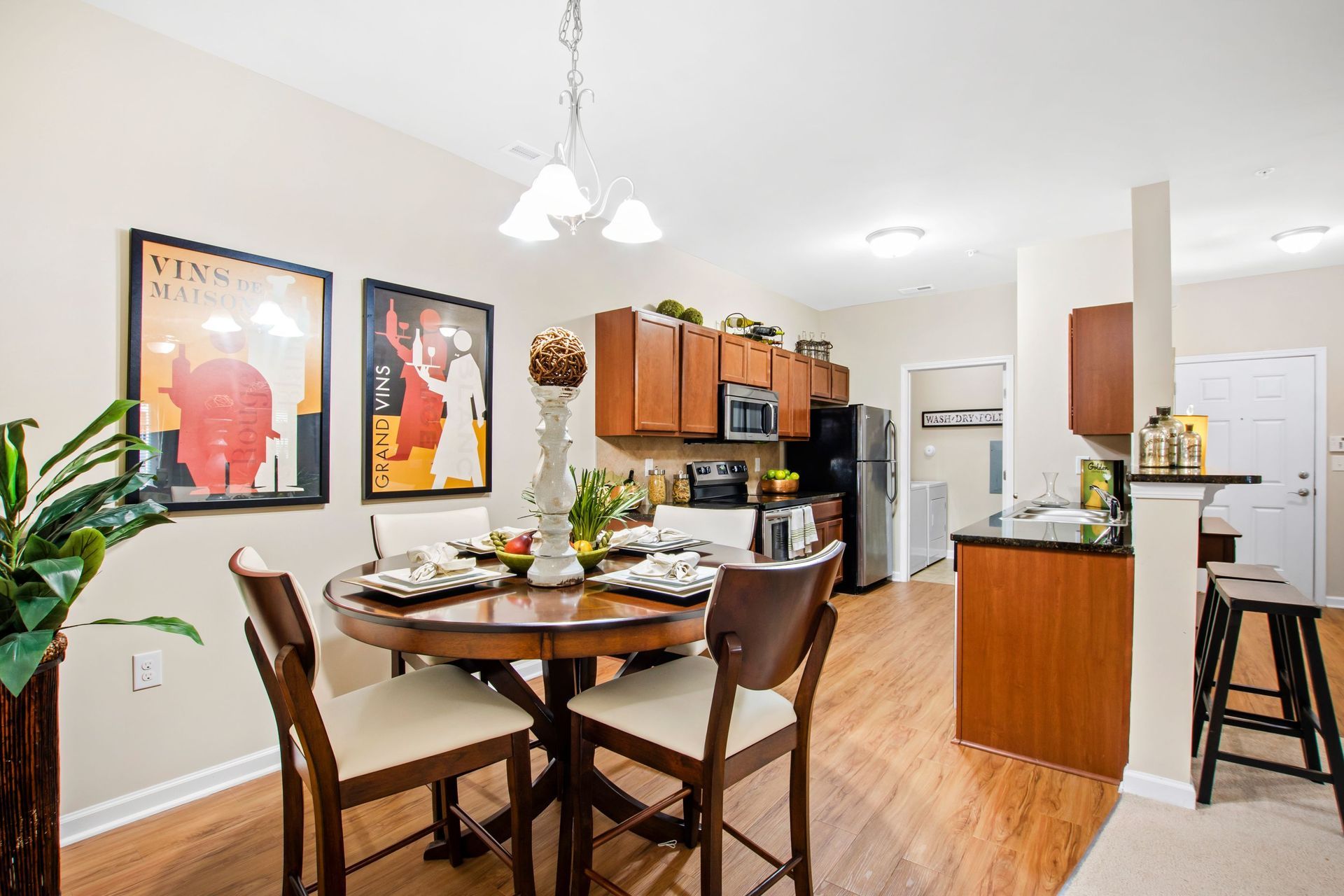 Open-concept dining area with round wood table and chairs beside a modern kitchen at Jack Britt.