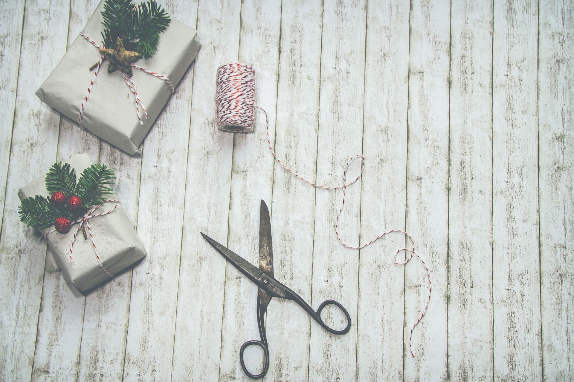 wrapped gifts on a wooden floor, with pink ribbon and scissors