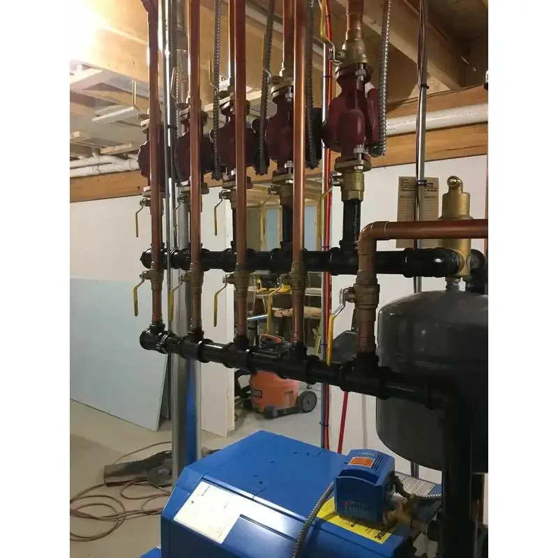 A blue boiler is sitting in a basement next to a bunch of pipes.