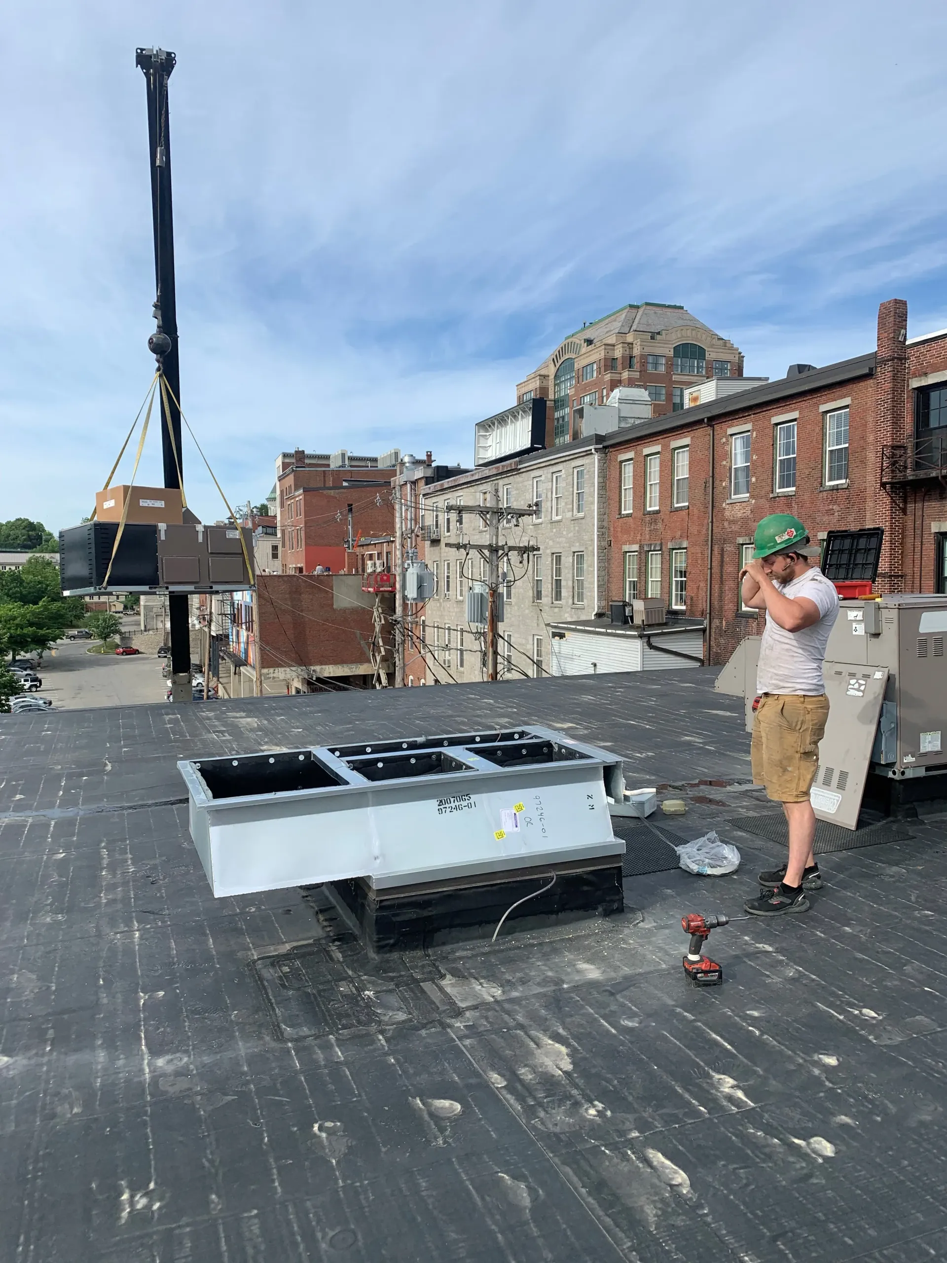 A man is standing on a roof next to a crane.