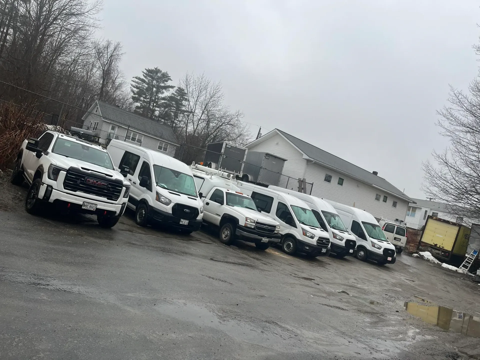 A row of white vans are parked in a parking lot.